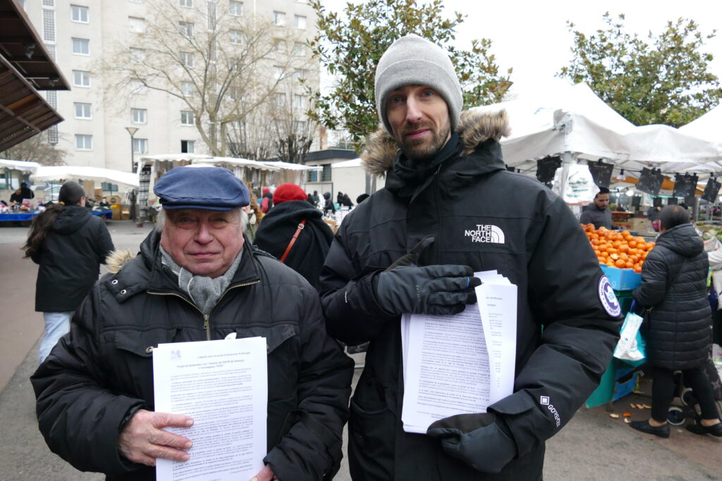 Jean-Marie Baty du MNLE 93 et Adil Champion distribuent des tracts sur le marché du Bourget pour alerter sur les risques d’un data center dans leur ville.